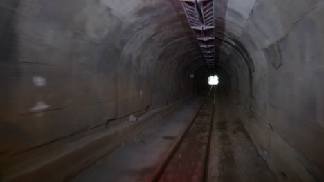 a journey through a dimly lit underground mine tunnel shows the tracks and surrounding walls, highlighting the unique environment and past mining activities.