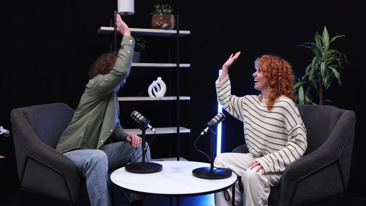 Two Young Adults High-Fiving in a Modern Podcast Studio