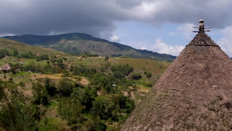 Traditional-cultural-Timorese-thatched-roof-sacred-house-with-panoramic-view-of-mountainous-rural-countryside-landscape-in-Timor-Leste,-Southeast-Asia