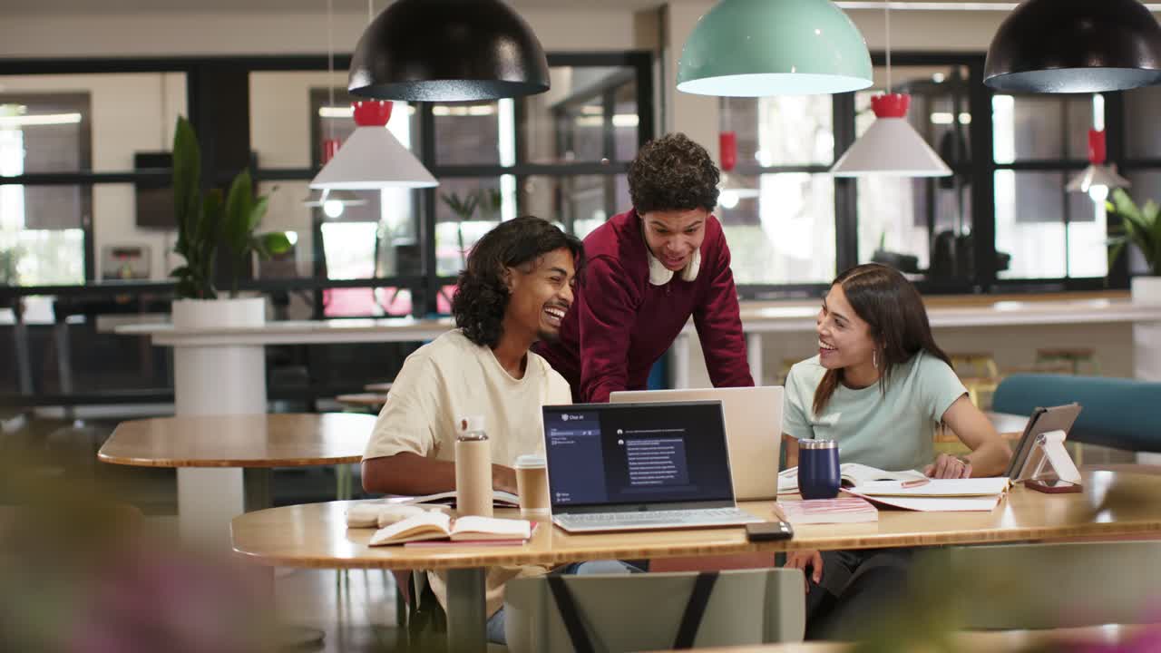 Afroamerikanischer Kollege mit Headset beugt sich in einer Lerngruppe über den Laptop und erklärt Notizen in der Bibliothek.