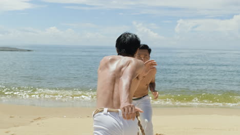 두 남자가 해변에서 카포에라를 춤추고 있다