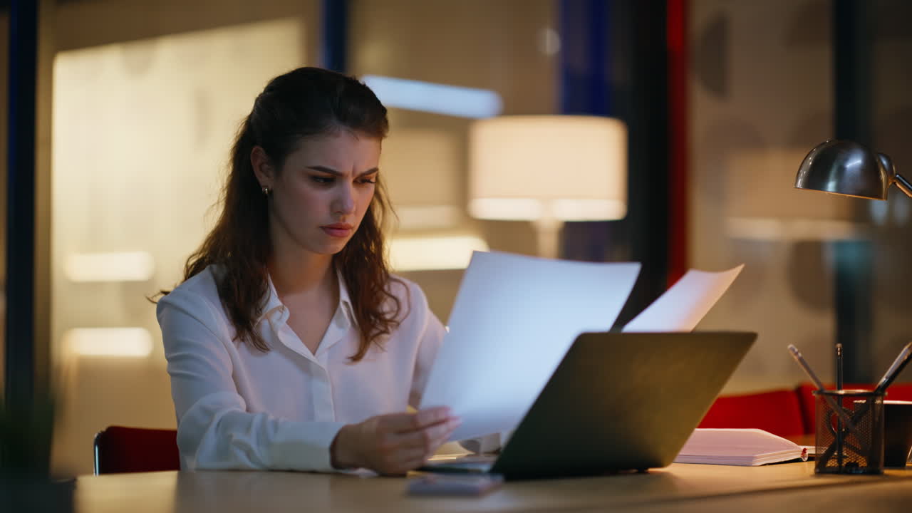 Accountant working late evening reviewing documents under lamp light closeup