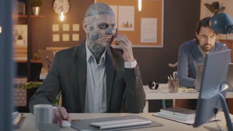 businessman with skull tattoo on phone call in office