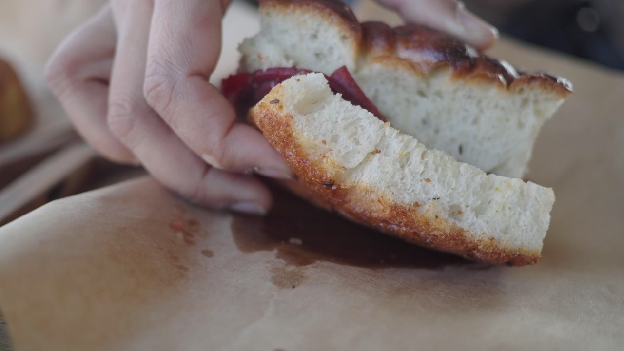 Hand Opening a Fresh Focaccia Sandwich with Salami and Tomato