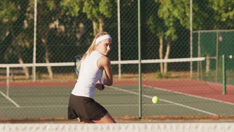 Video-of-focused-caucasian-female-tennis-player-holding-racket-and-hitting-ball