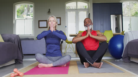 Pareja-Mayor-De-Raza-Mixta-Practicando-Yoga-Juntos-En-Casa