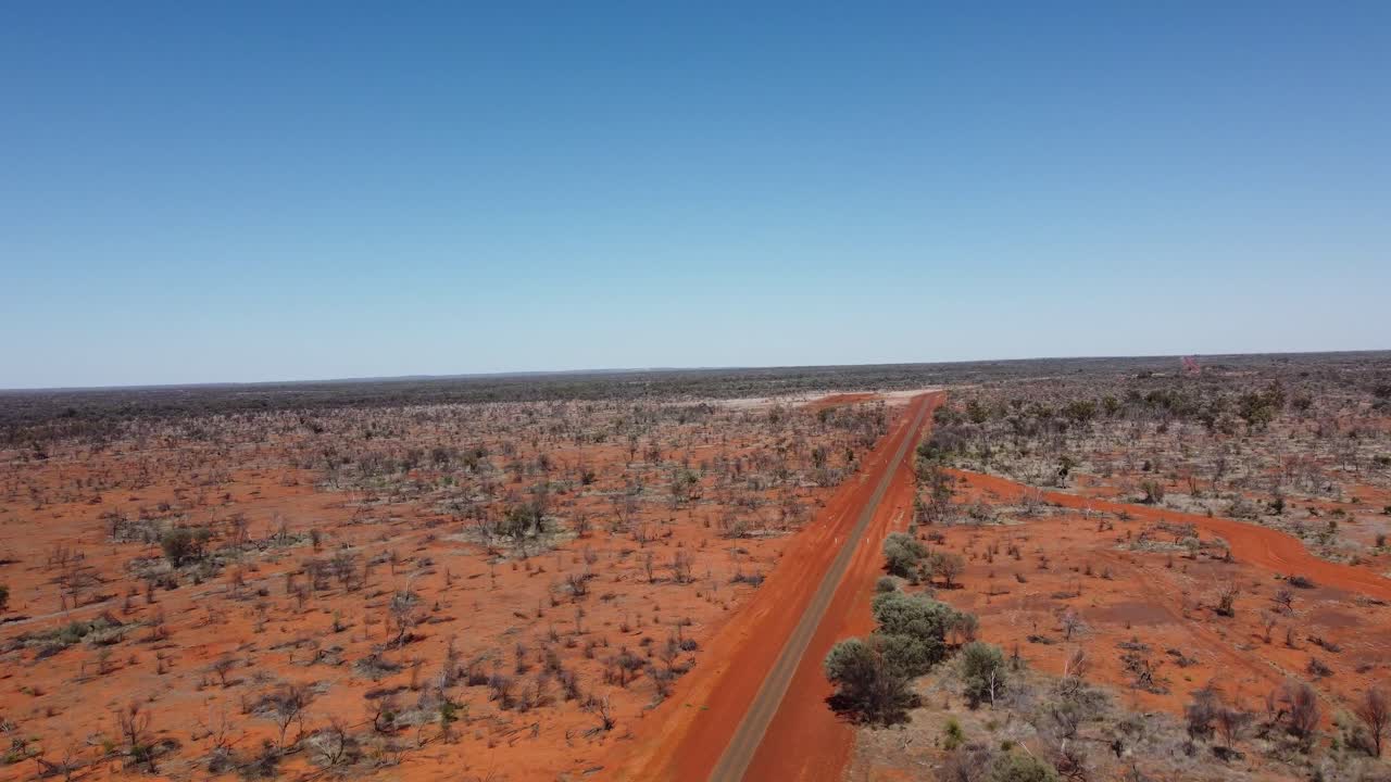 Drone terbang menuju persimpangan jalan beraspal dan jalan tanah di pedalaman Australia.