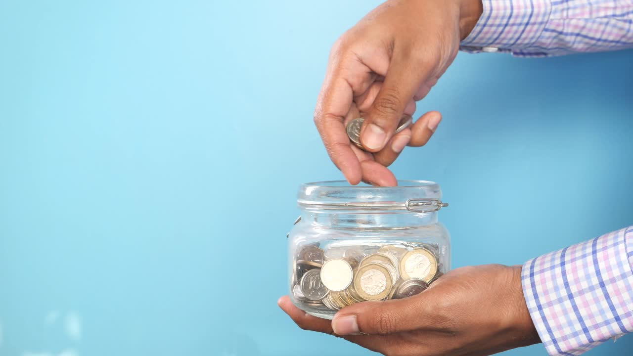 Person Saving Money in a Glass Jar