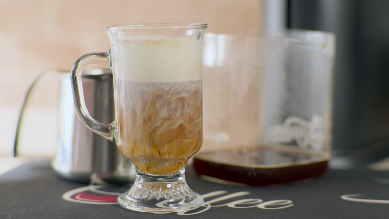 A creamy stream of milk swirls into rich coffee in a clear glass mug, creating a mesmerizing blend of textures and tones capturing the essence of a fresh café pour