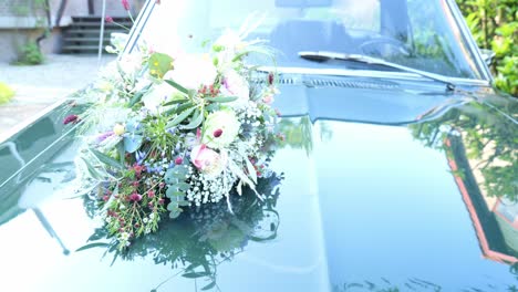 classic green ford mustang with a flower bouquet on the hood, parked outdoors on a sunny day