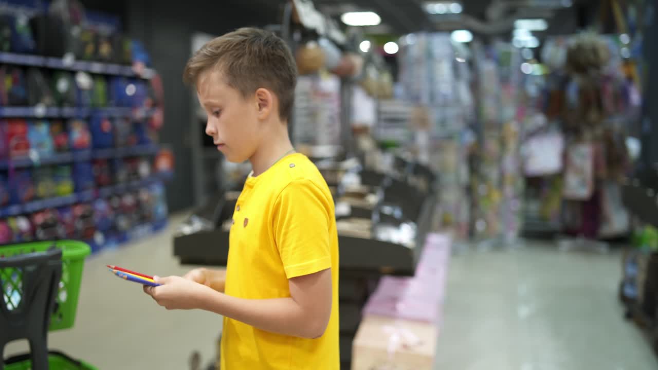 Boy buying stationery for school. Boy in stationery store buying pens holding them