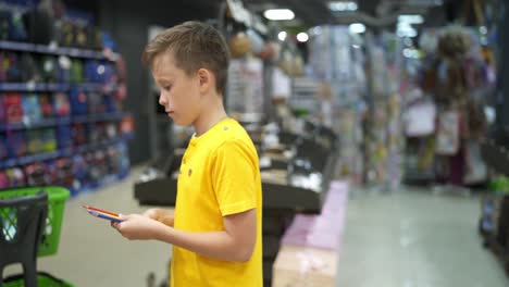 boy buying stationery for school. boy in stationery store buying pens holding them