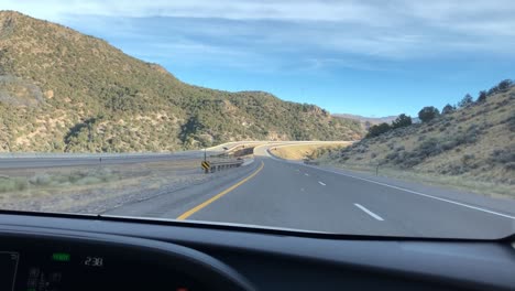 Driving-towards-huge-mountains-on-empty-desert-road