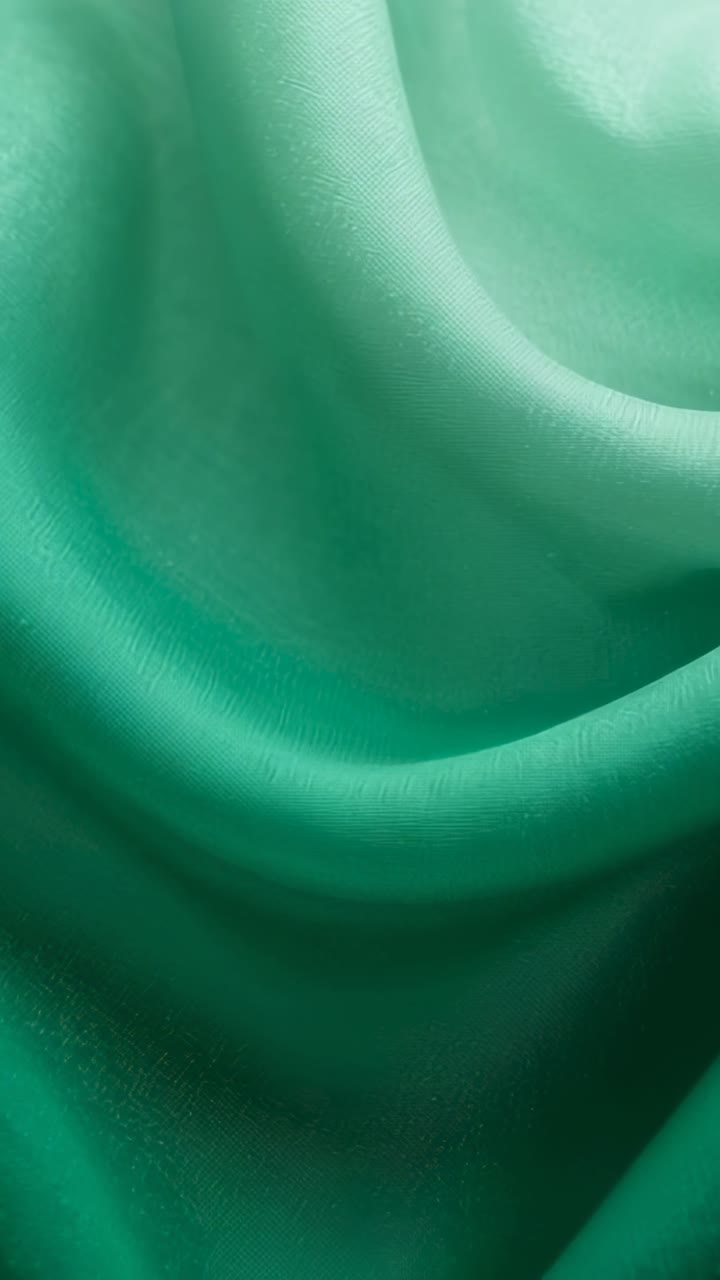 Vertical video: Lighting shifting, green drape showing folds, ridges in studio revealing texture