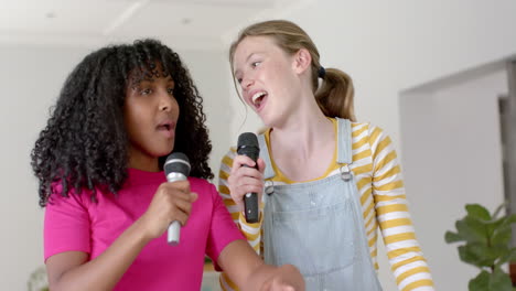 happy diverse teenage female friends dancing and singing at home, slow motion