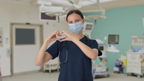 happy indian female doctor showing heart sign with mask