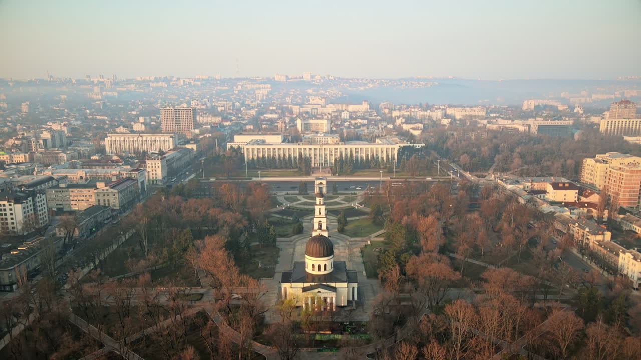 Aerial drone view of Chisinau downtown. View of Central park, Cathedral, Goverment, roads with moving cars and bare trees. Sunny weather, fog. Moldova