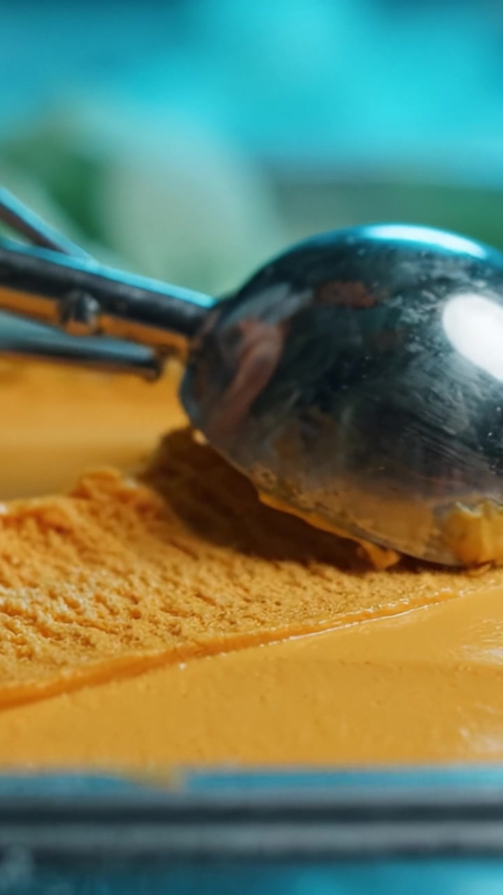 Un primo piano di un dessert arancione liscio e cremoso con una superficie testurizzata, catturato con dettagli mozzafiato e colori vivaci, perfetto per gli appassionati di cucina.