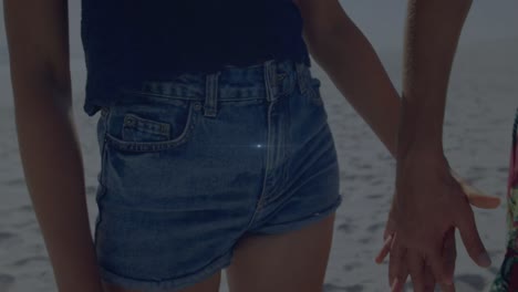 spot of light against mid section of a african american couple holding hands at the beach