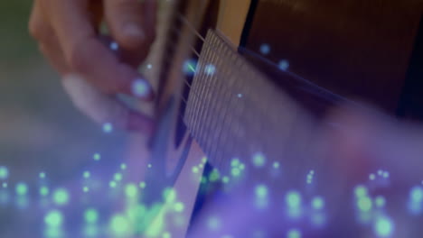 guitar player pressing steel strings on fretboard in music studio, with floating blue light