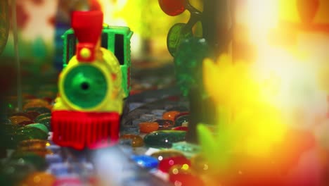 Bunte-Spielzeugeisenbahn,-Die-Sich-Vor-Der-Kamera-Auf-Schienen-Bewegt.-Nahaufnahme-Der-Kindereisenbahn