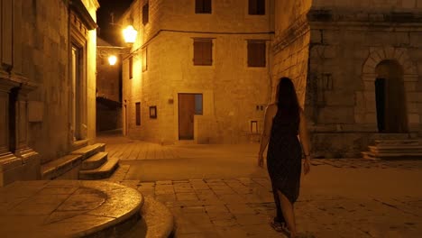 woman walking in streets of historical old town summer evening, crane shot