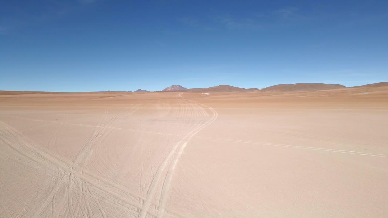 Dramatic drone shot over sand dunes with bold shadows cast in late afternoon Bolivia light