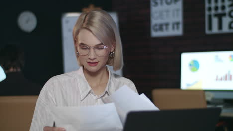 Cheerful-business-woman-working-on-laptop-in-office.-Closeup-girl-checking-paper