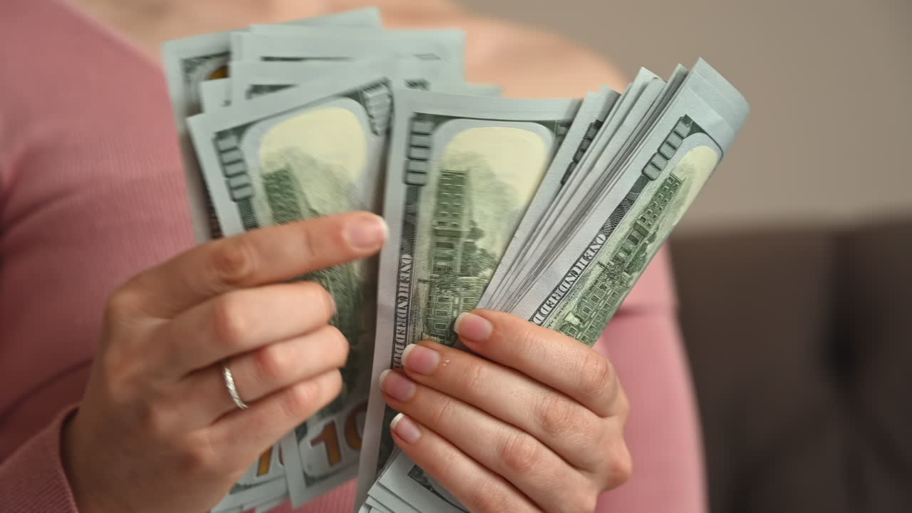 Smiling woman counting multiple one hundred dollar bills in her hands