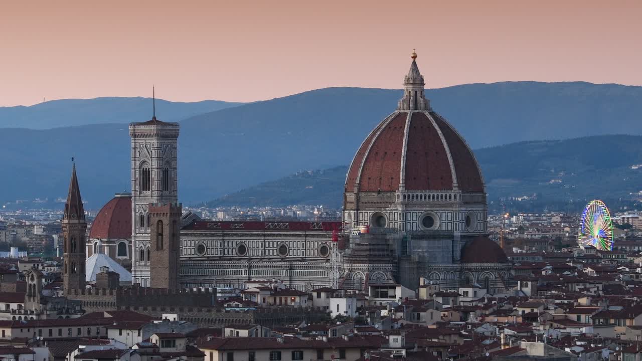 피렌체의 산타 마리아 델 피오레 대성당은 미란젤로 광장에서 볼 수 있으며, 왼쪽 배경에는 조명된 페리스 이 있습니다.