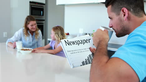 Father-reading-the-newspaper-while-family-has-breakfast