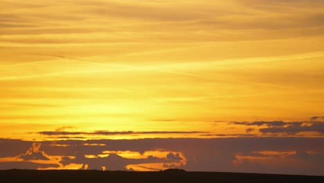 beautiful sunset with golden sky and layers of flat clouds below. gorgeous natural setting sun footage. nature background wallpaper footage.