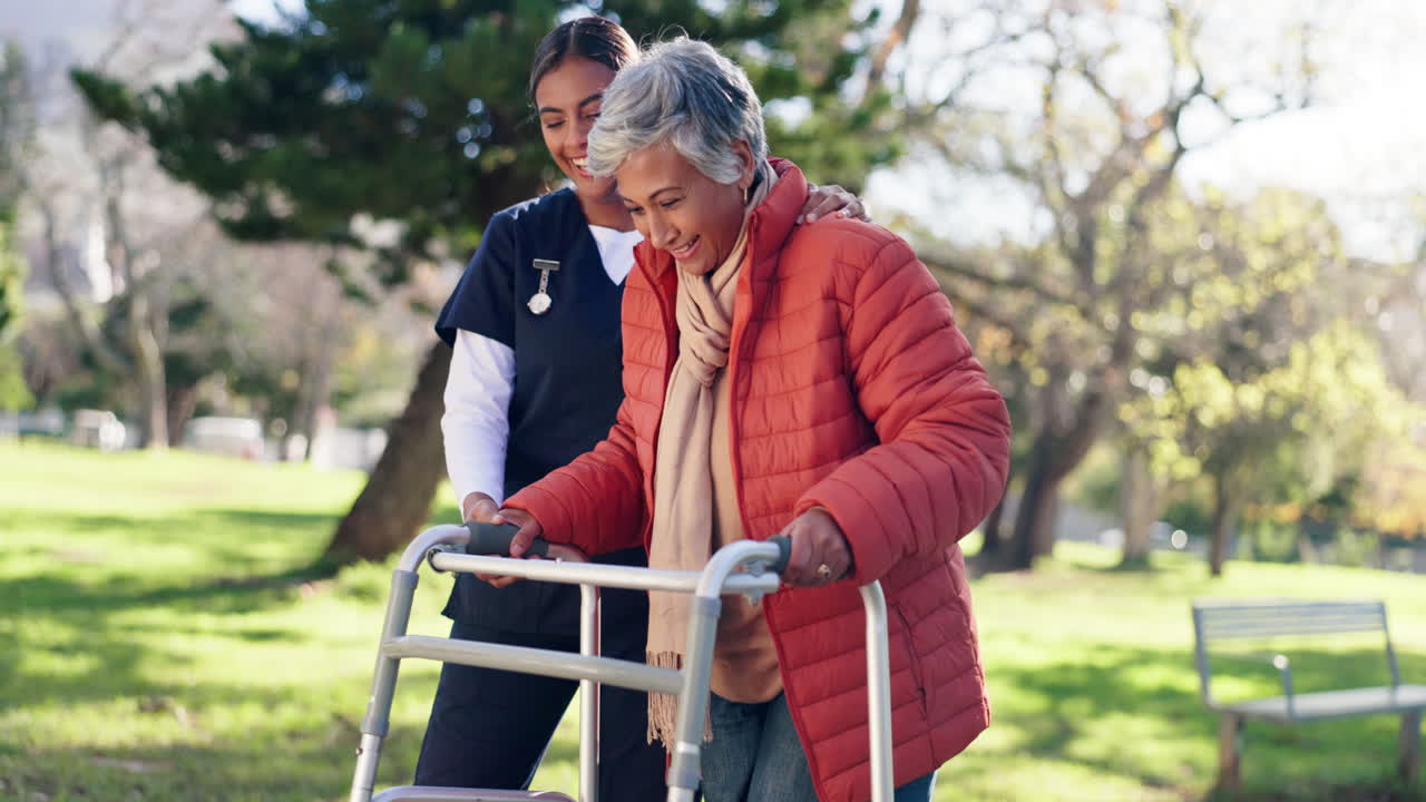 Caregiver assisting senior woman with walker in the park