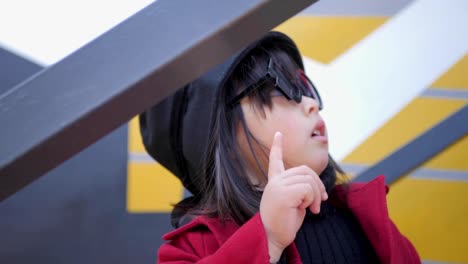 korean girl in a red coat and cap and round glasses sit on the iron staircase the street in autumn