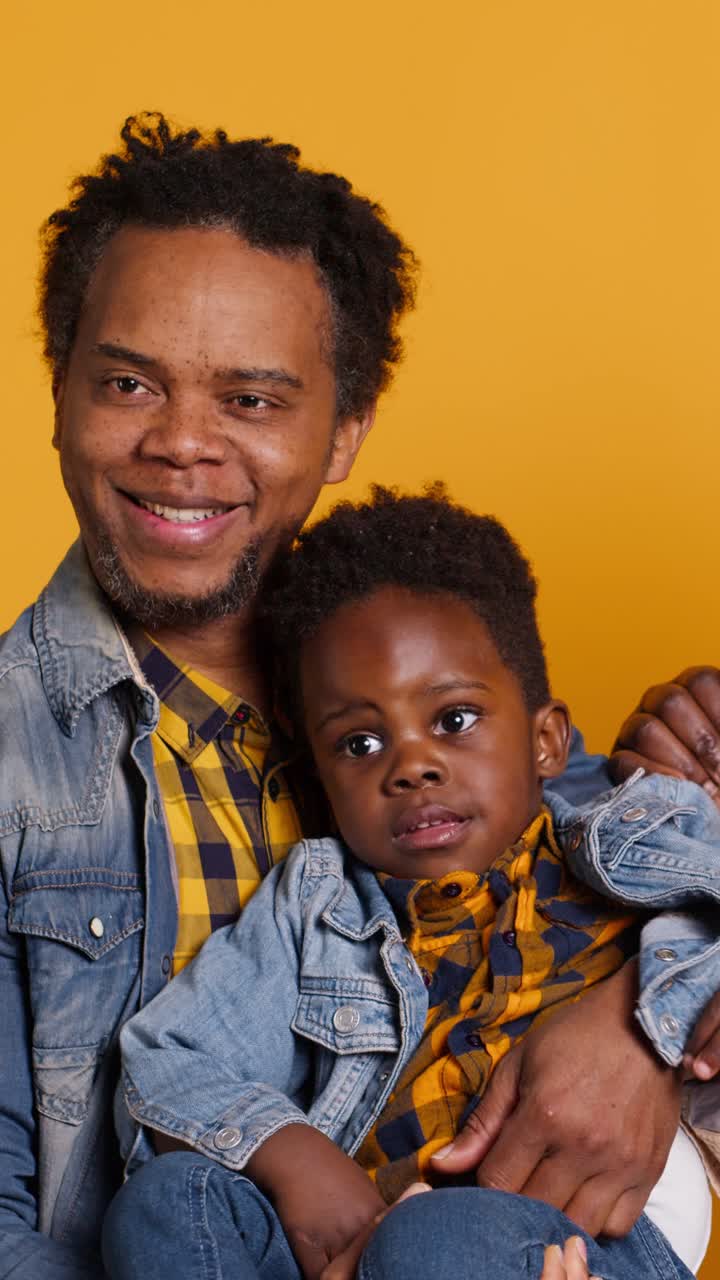Felice padre afroamericano e figlio sorridenti su sfondo giallo