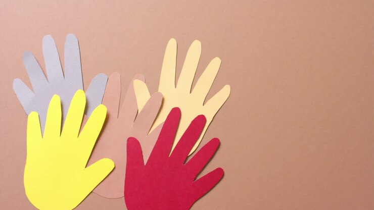 Primer plano de manos unidas hechas de papel de colores sobre fondo marrón con espacio de copia.
