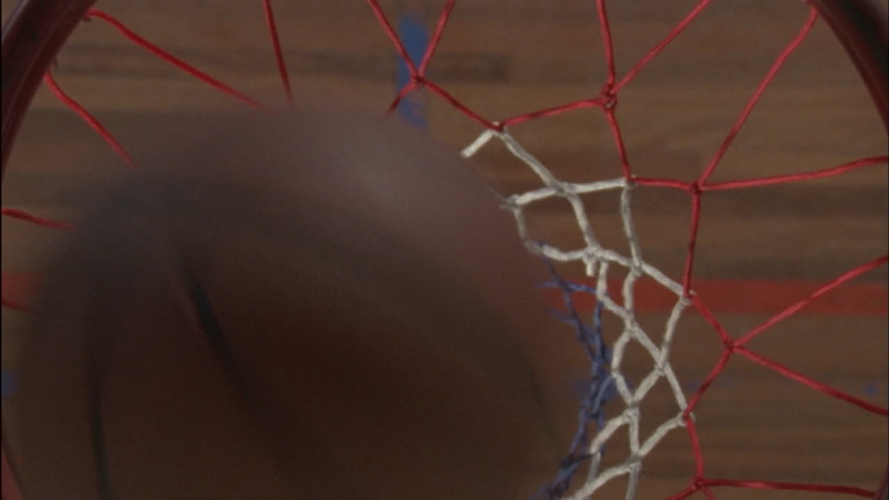 una pelota de baloncesto entra en la red y un jugador la recoge