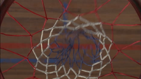 una pelota de baloncesto entra en la red y un jugador la recoge