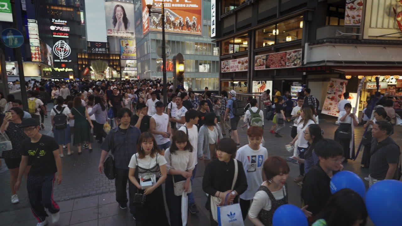 Intersection filled with people walking and sight seeing at Dotonbori, Osaka, Japan, wide three hundred sixty degree shot in slow motion.