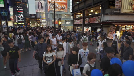 intersection filled with people walking and sight seeing at dotonbori, osaka, japan, wide three hundred sixty degree shot in slow motion.