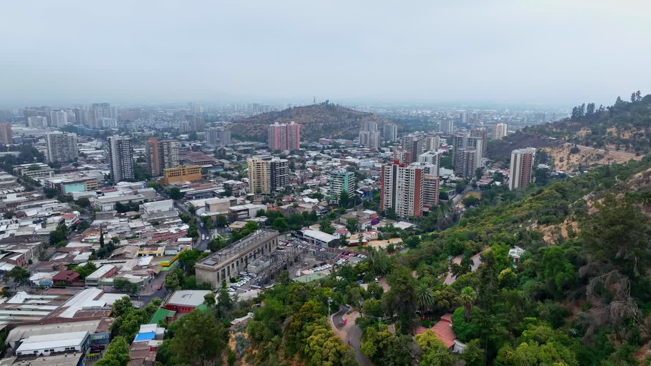 Aerial View of Residential and Mid‑Rise Buildings Near Hills and Forested Areas in Santiago on an Overcast Day
