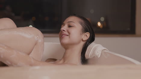 close up view of a woman taking a bath while rubbing her legs with soap