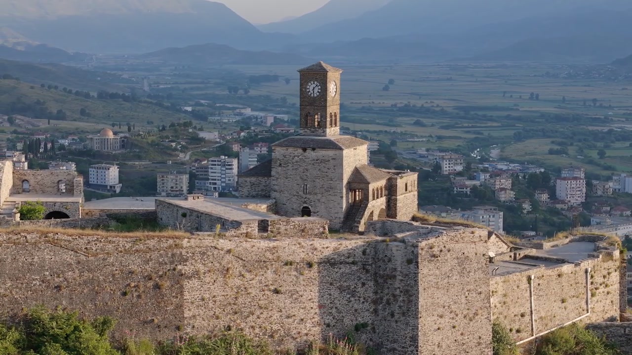 Torre dell'orologio del Castello di Gjirokastra all'alba, vista aerea con drone in orbita con la città sullo sfondo