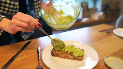 una mujer haciendo tostadas de aguacate.