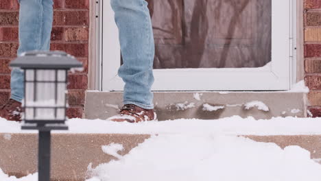 Low-Pov-Aufnahme-Eines-Mannes,-Der-Schnee-Von-Der-Veranda-Schaufelt