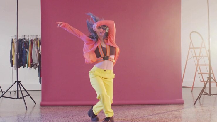NB dancer opening arms dancing, modeling fashion on pink set glitch across frame obscuring subject