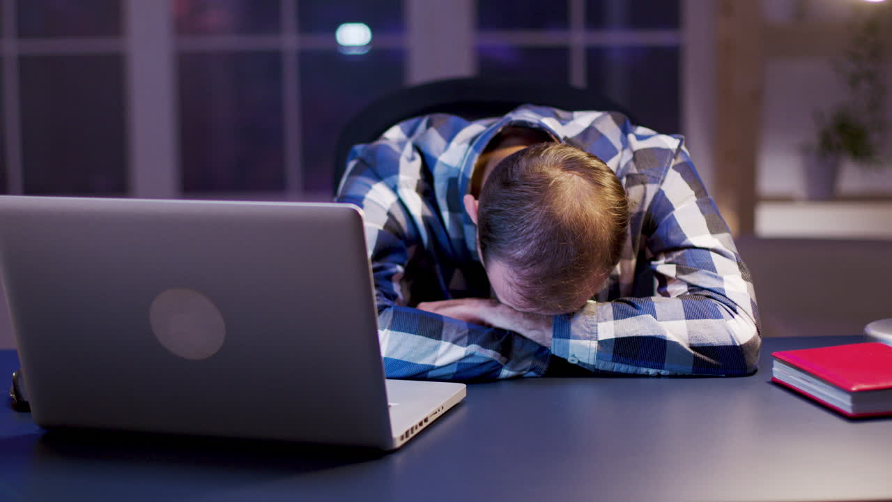 Tired Businessman Sleeping at Desk with Laptop