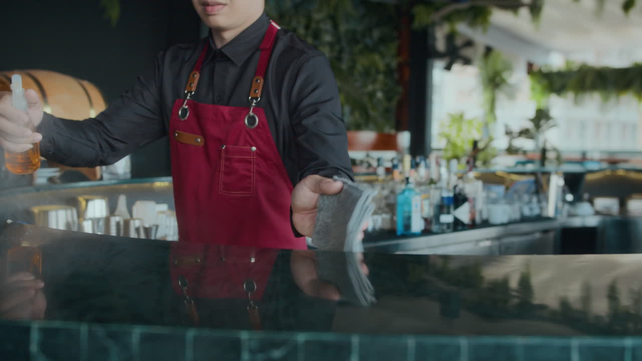 Waiter Disinfecting Surface of Bar Counter in Cafe