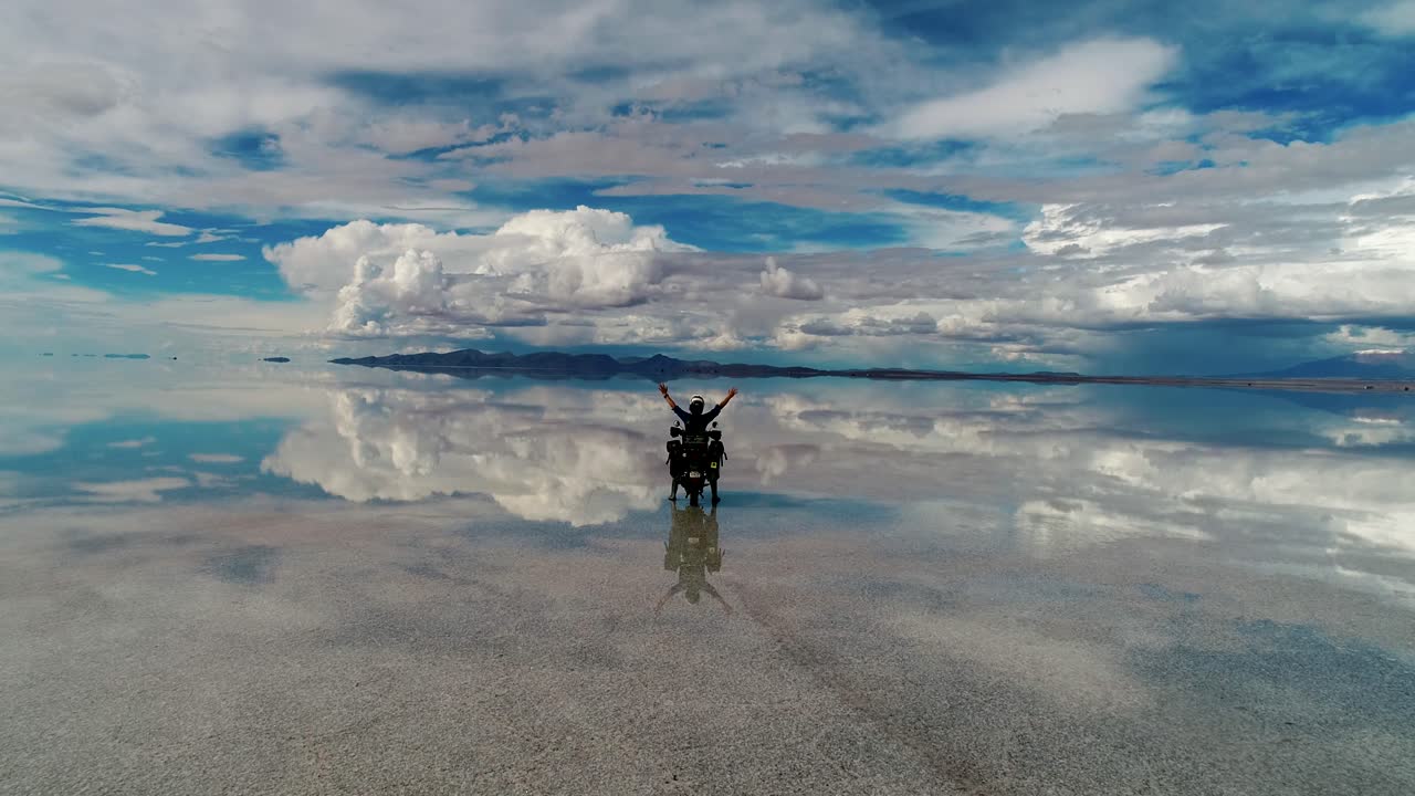 Salt flat in Bolivia Uyuni South America during wet season. Motorcycle rider Mirror reflection off the water. Filmed on DJI Drone Phantom Pro