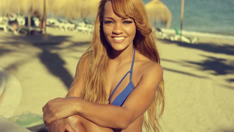 chica africana en bikini descansando en el banco de la playa